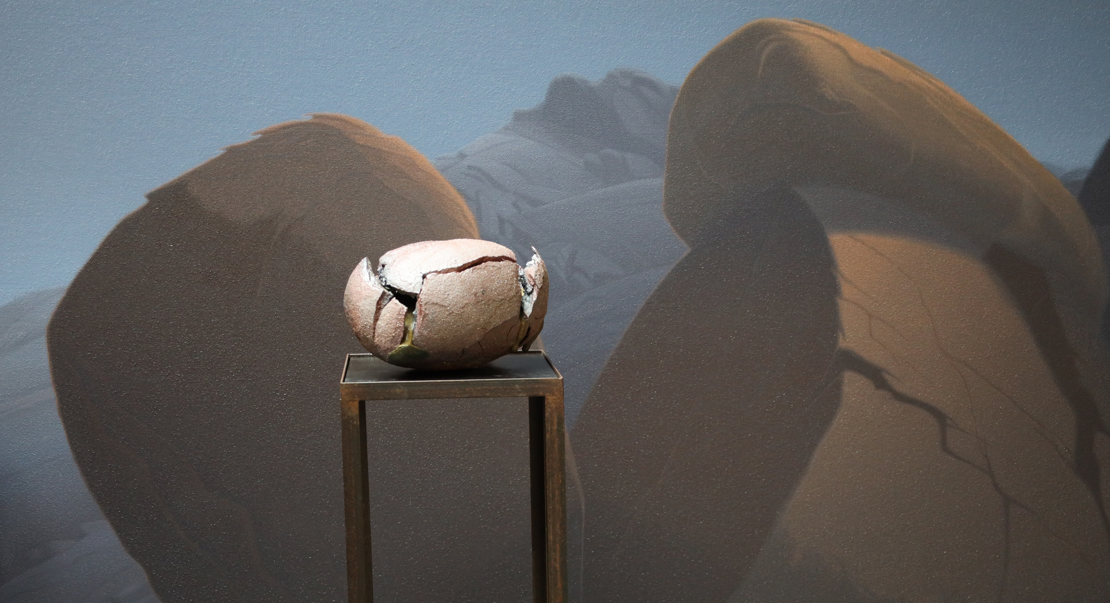 Keramik-Objekt vor gemalter Wüstenlandschaft in Braun und Blau