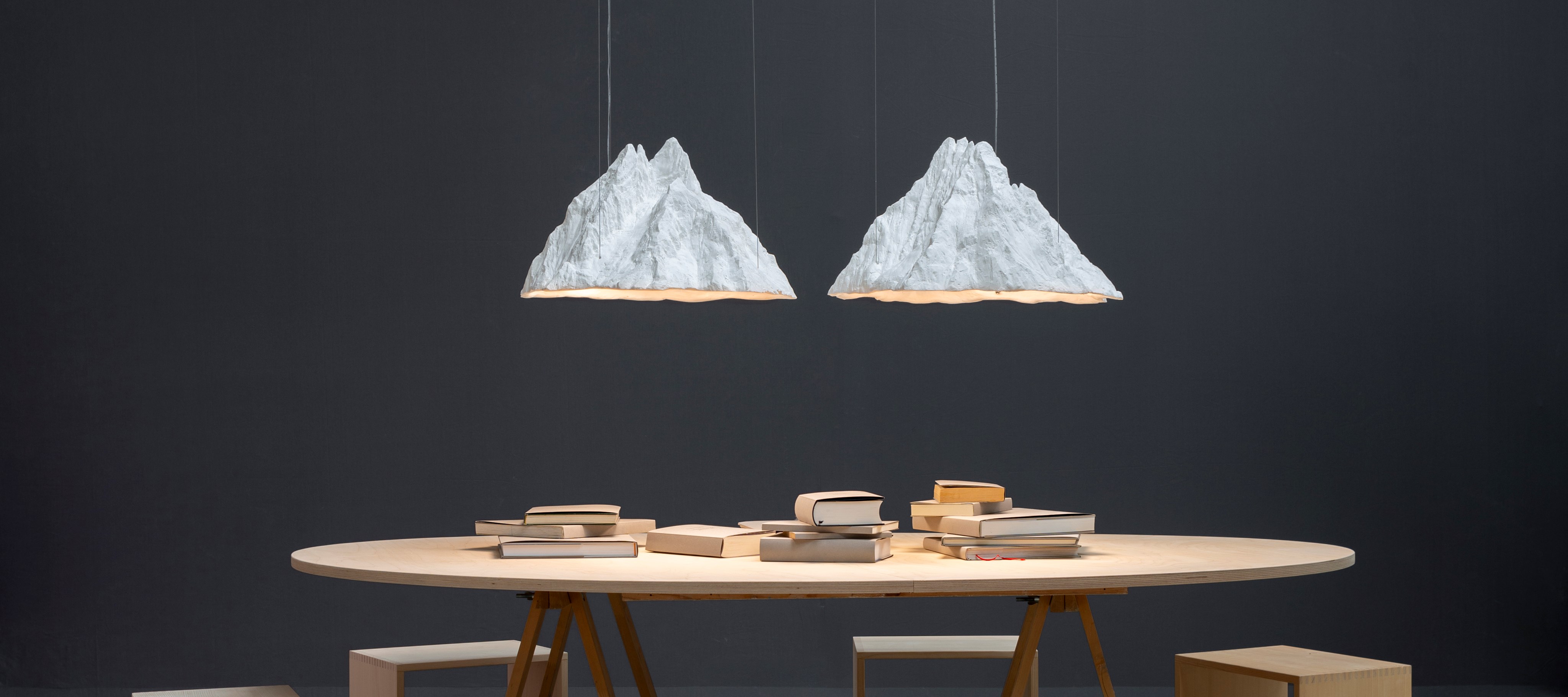 Zwei Alpengipfel aus Gibs als Lampenschirm über Tisch mit Büchern