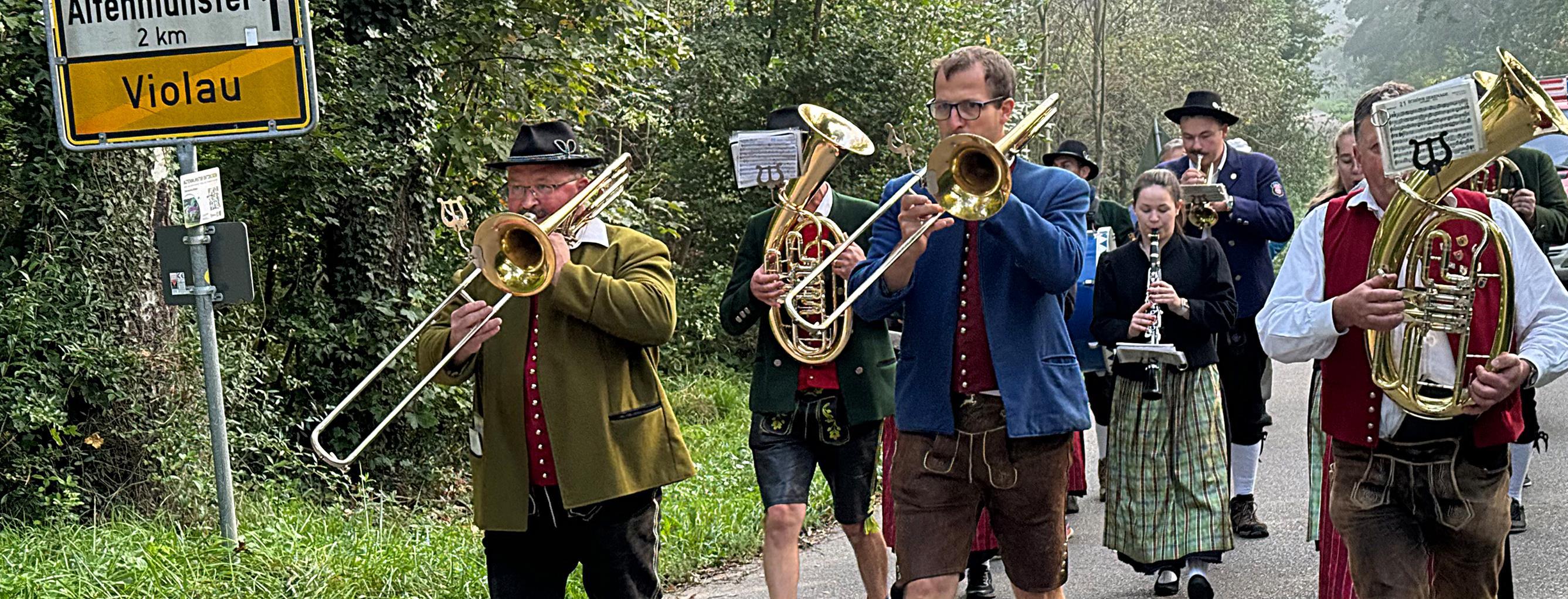 Gruppe von marschierenden Blasmusikern und Musikerinnen in Tracht