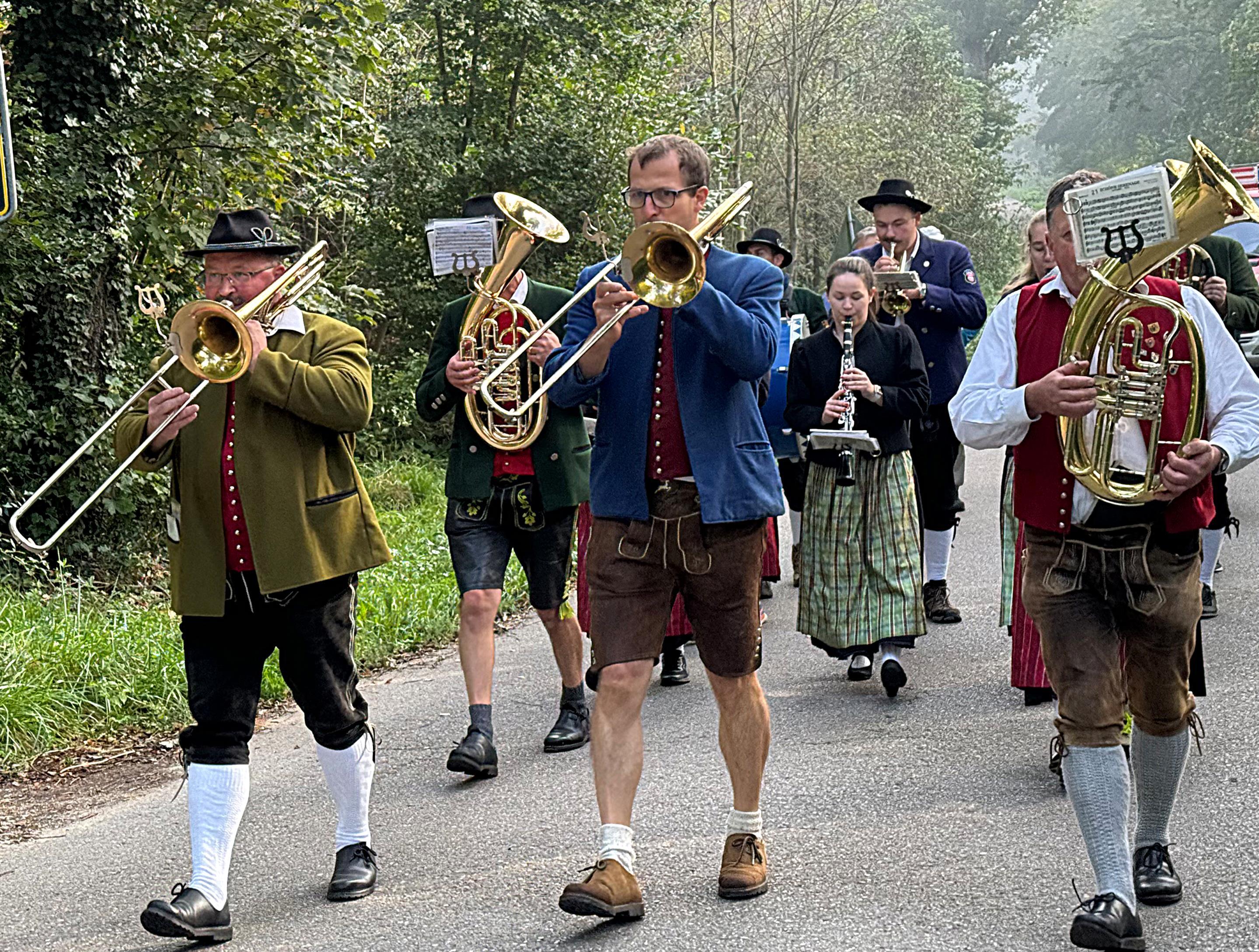 Gruppe von marschierenden Blasmusikern und Musikerinnen in Tracht
