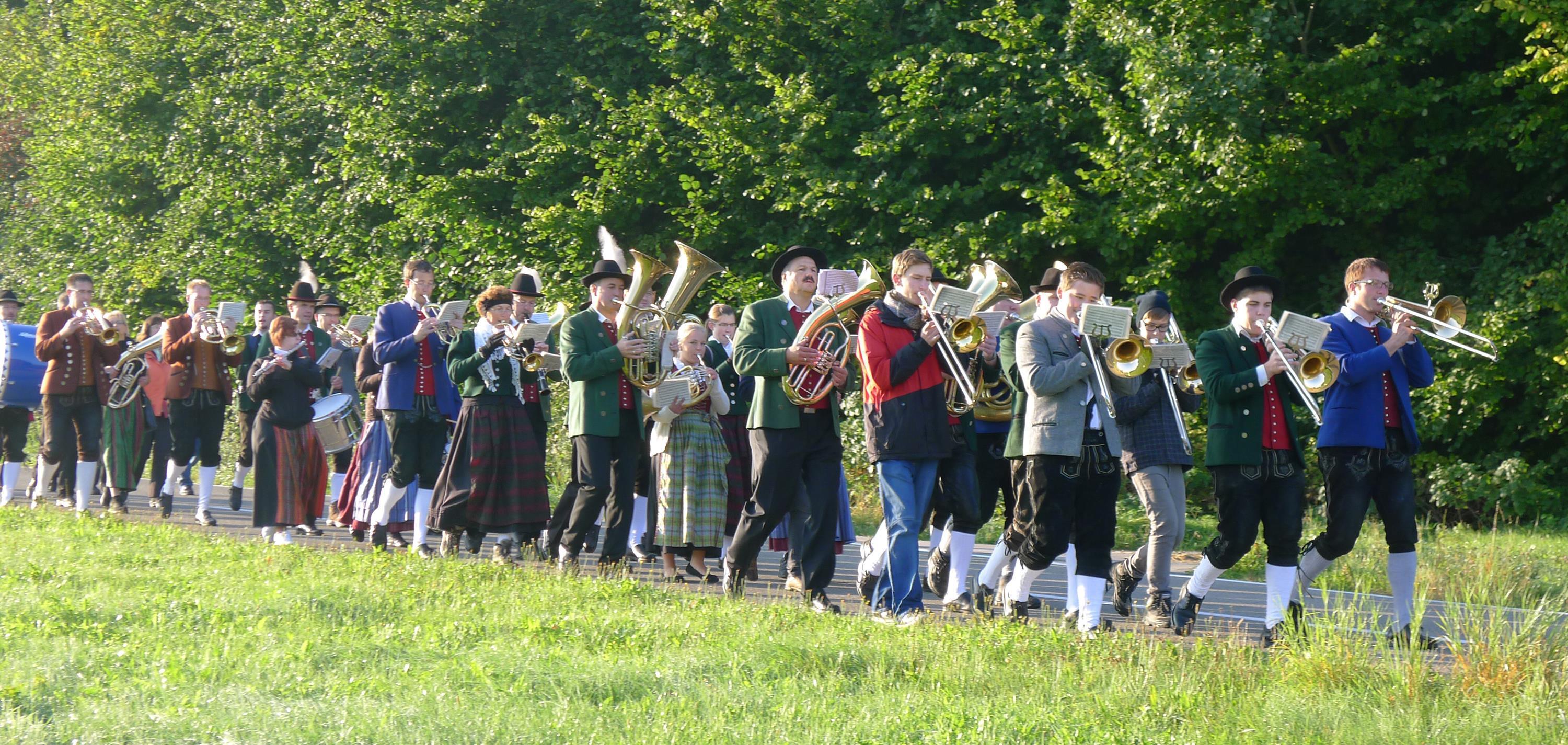 Gruppe von marschierenden Blasmusikern und Musikerinnen in Tracht