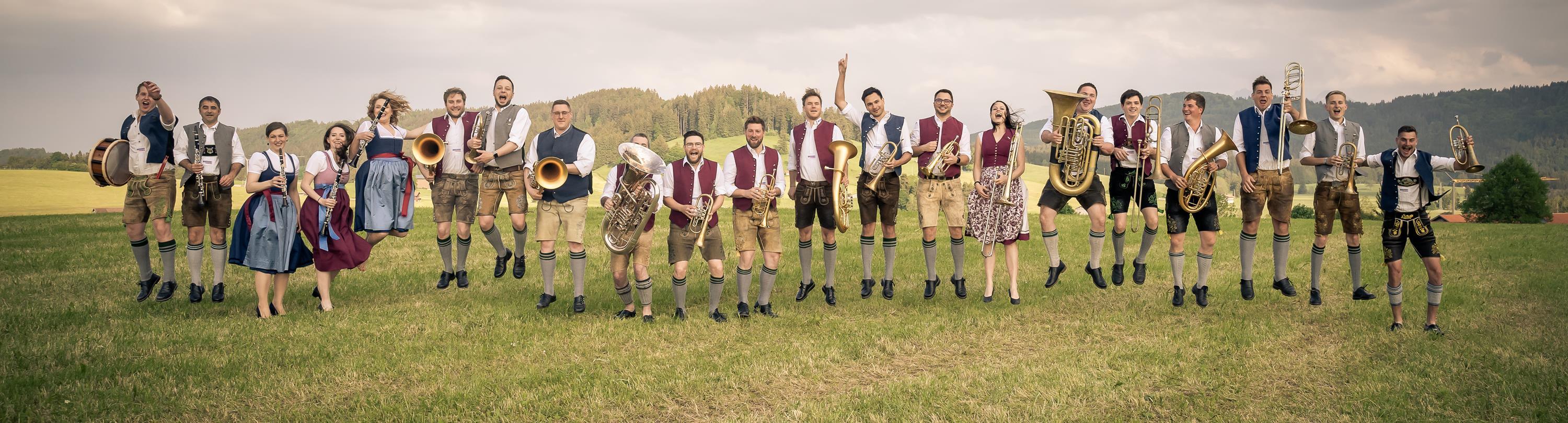 18 Musiker mit Instrumenten auf einer Wiese