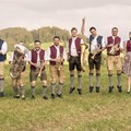 18 Musiker mit Instrumenten auf einer Wiese