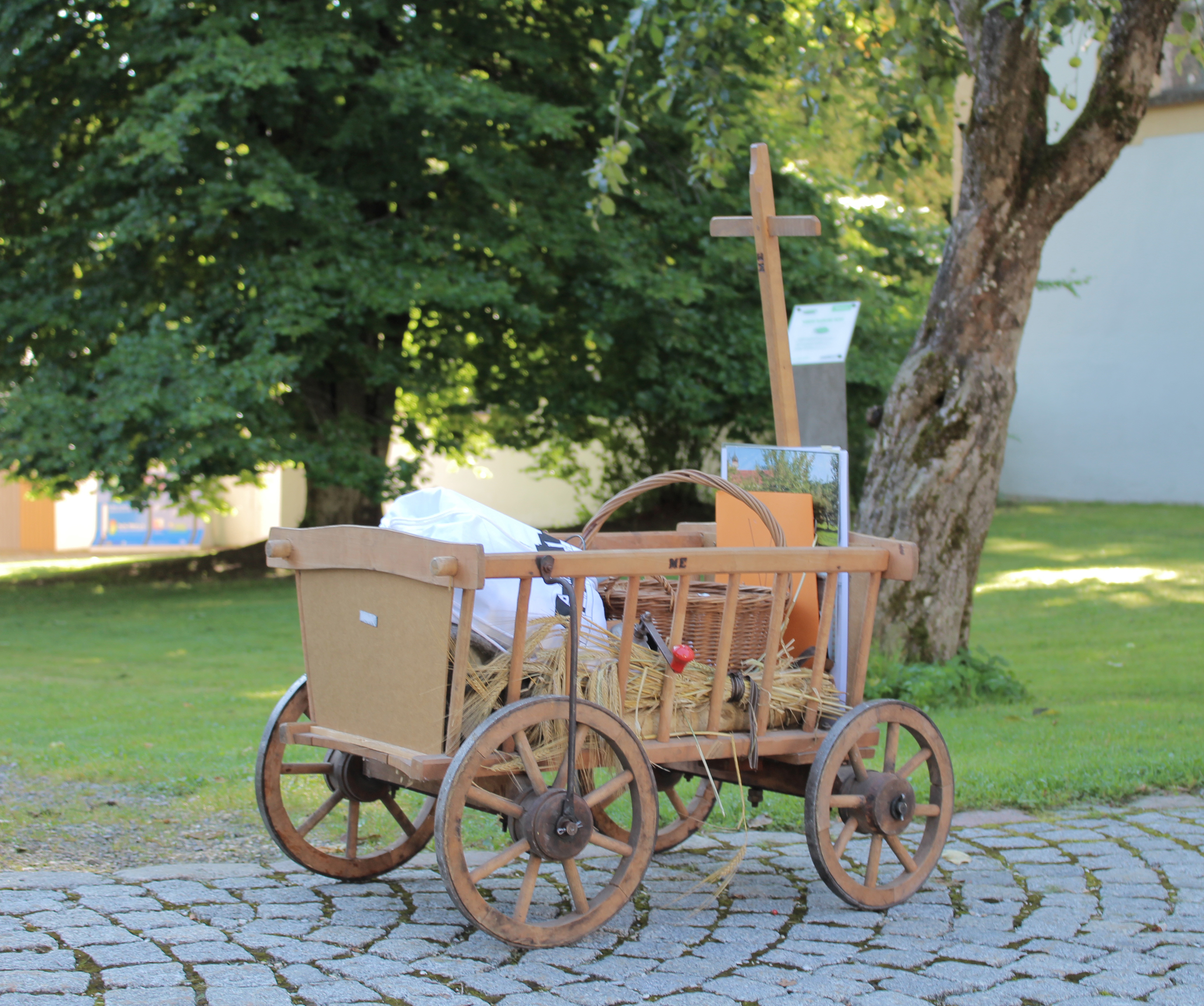 Leiterwagen gefüllt mit historischen Objekten wie Getreidesieb oder Wäschestampfer