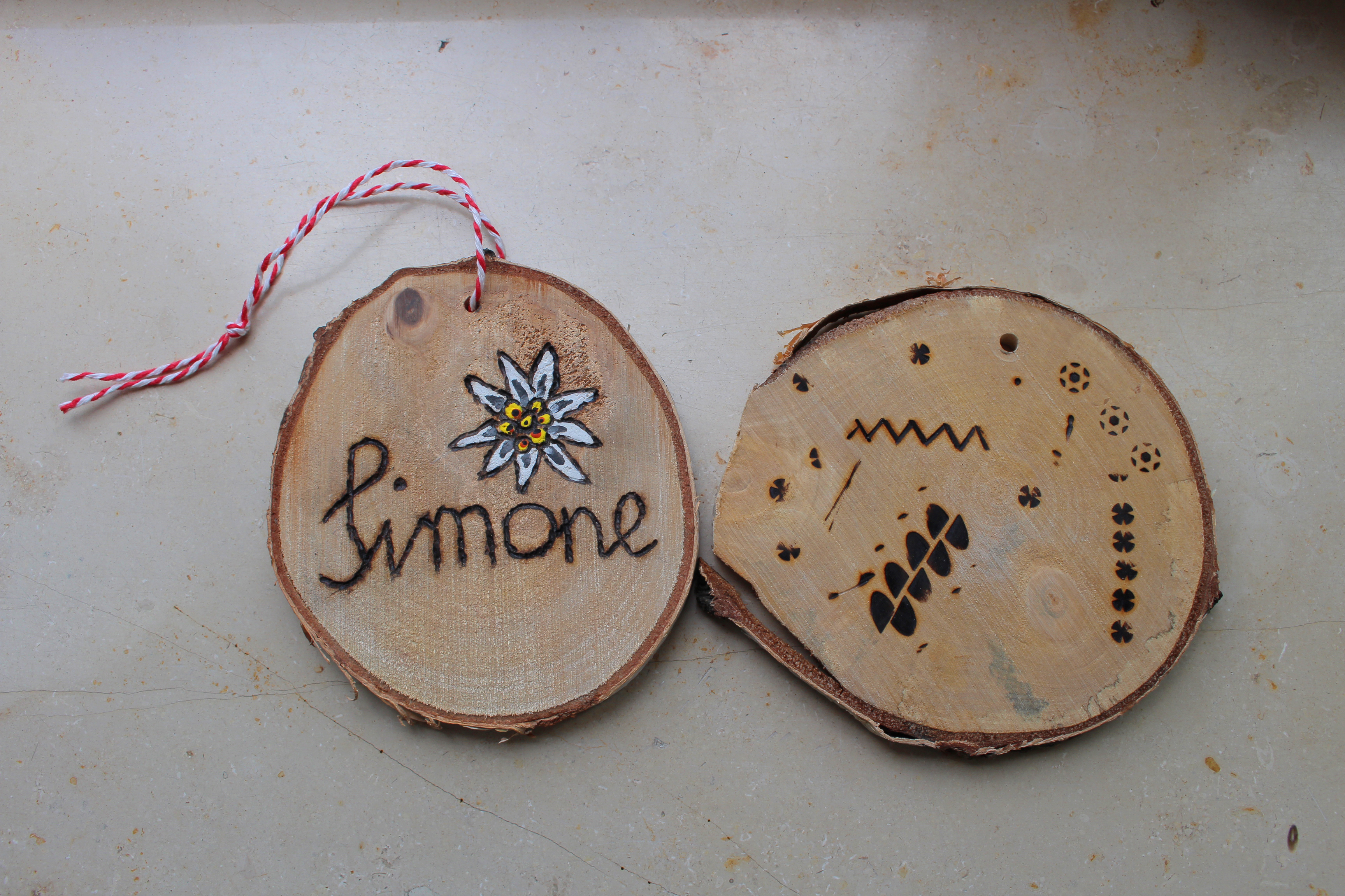 Zwei kleine Baumscheiben mit eingebranntem Muster und Namen: Simone