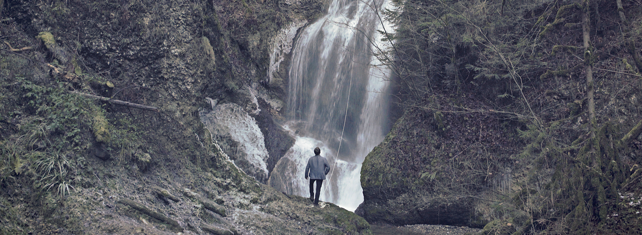 Wanderer betrachtet Landschaft mit Wasserfall