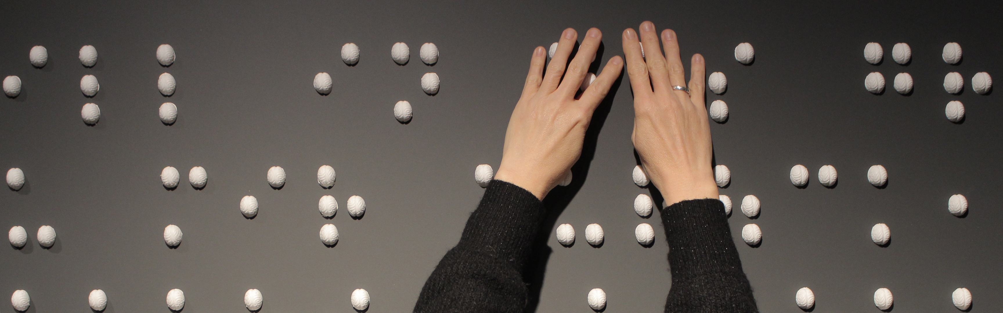 Finger ertasten weiße Elemente in Braille-Schrift